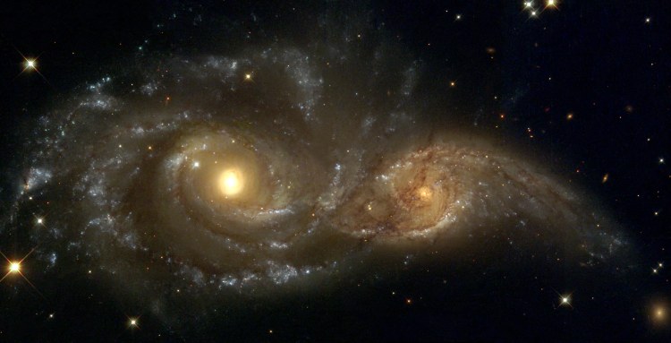 Spiral galaxies in collision: Billions of years from now, only one of these two galaxies will remain. Until then, spiral galaxies NGC 2207 and IC 2163 will slowly pull each other apart, creating tides of matter, sheets of shocked gas, lanes of dark dust, bursts of star formation, and streams of cast-away stars.